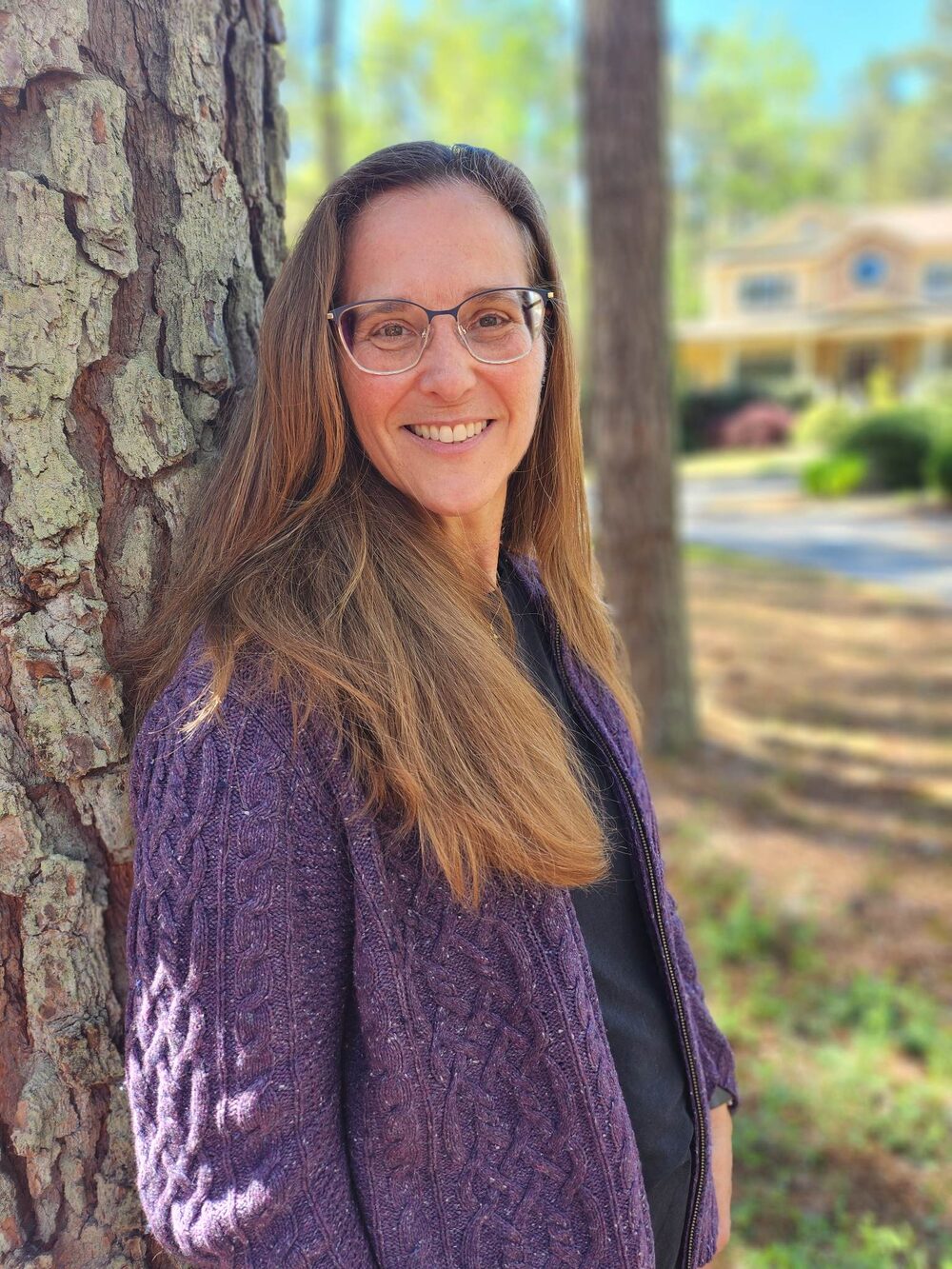 Heather Wilson, founder of Apex NeuroCare, leaning against a tree